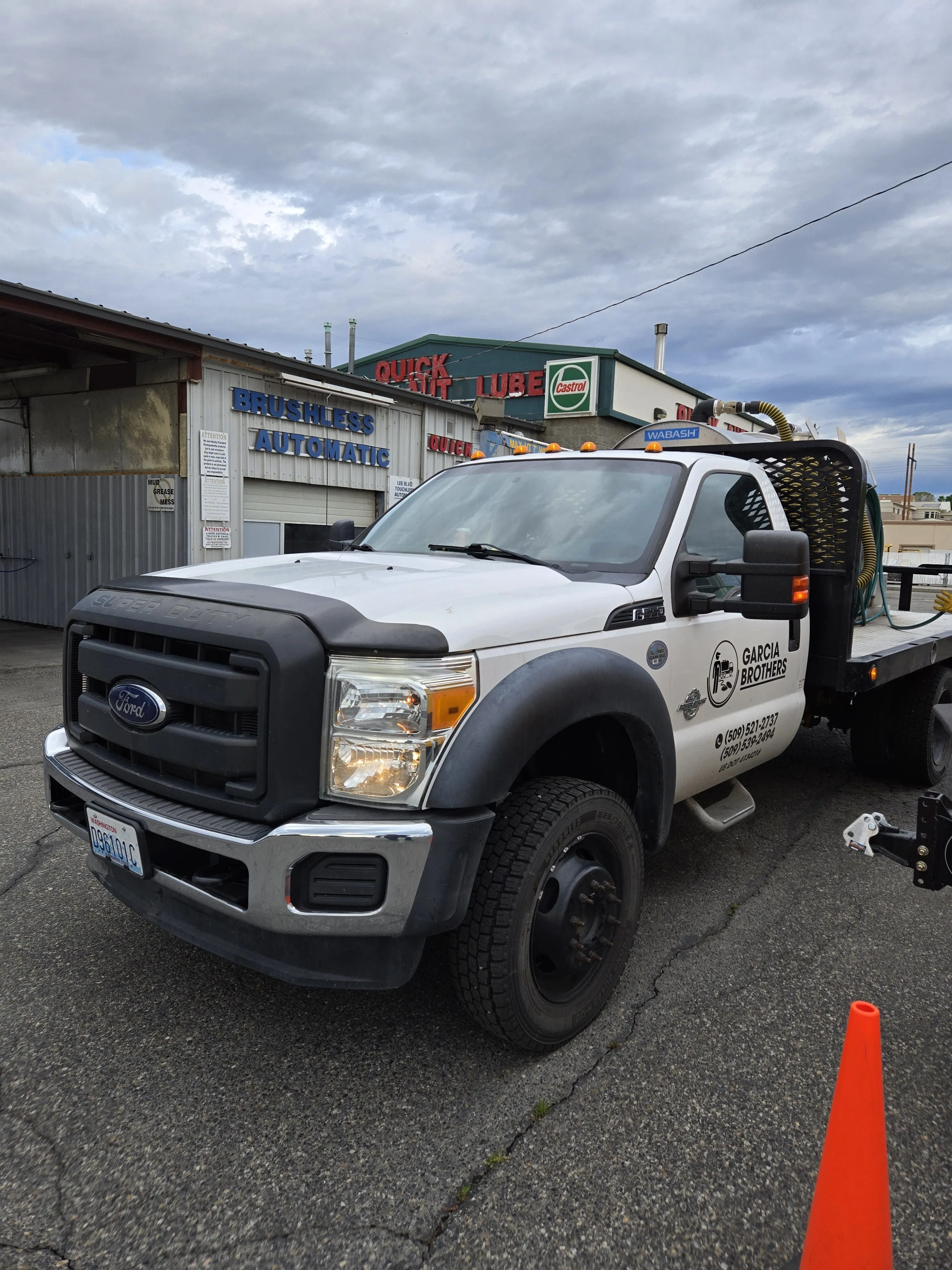 A white Garcia Brothers service truck parked at a Tri-Cities shop with an orange safety cone beside it