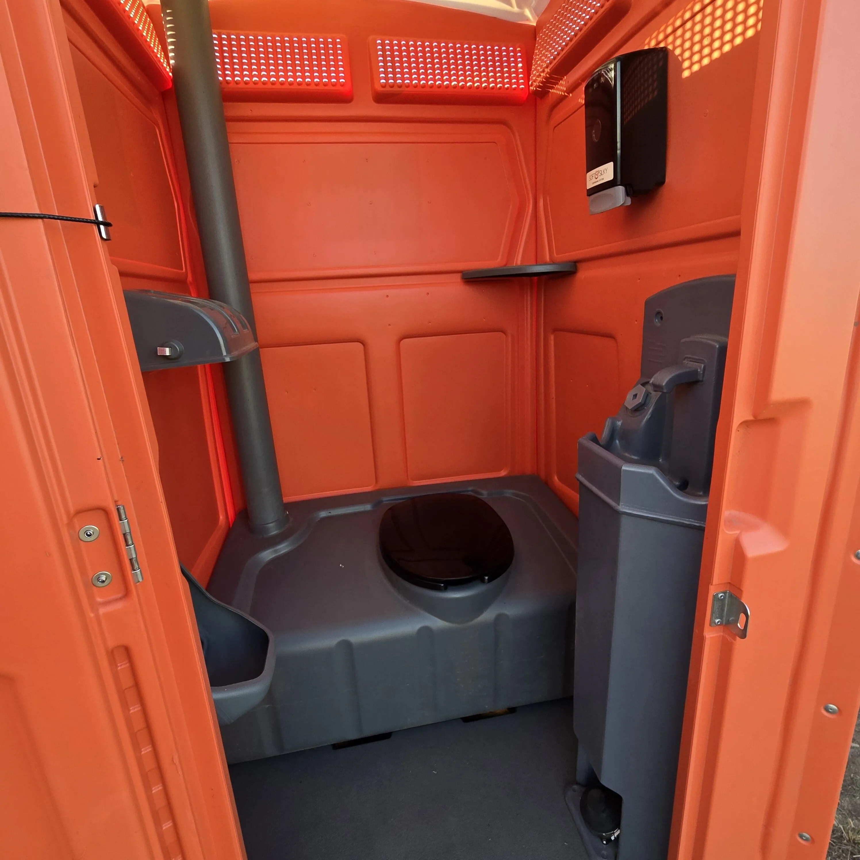The interior of a Garcia Brothers portable toilet with a sink unit, soap dispenser, and paper-towel station for full handwashing